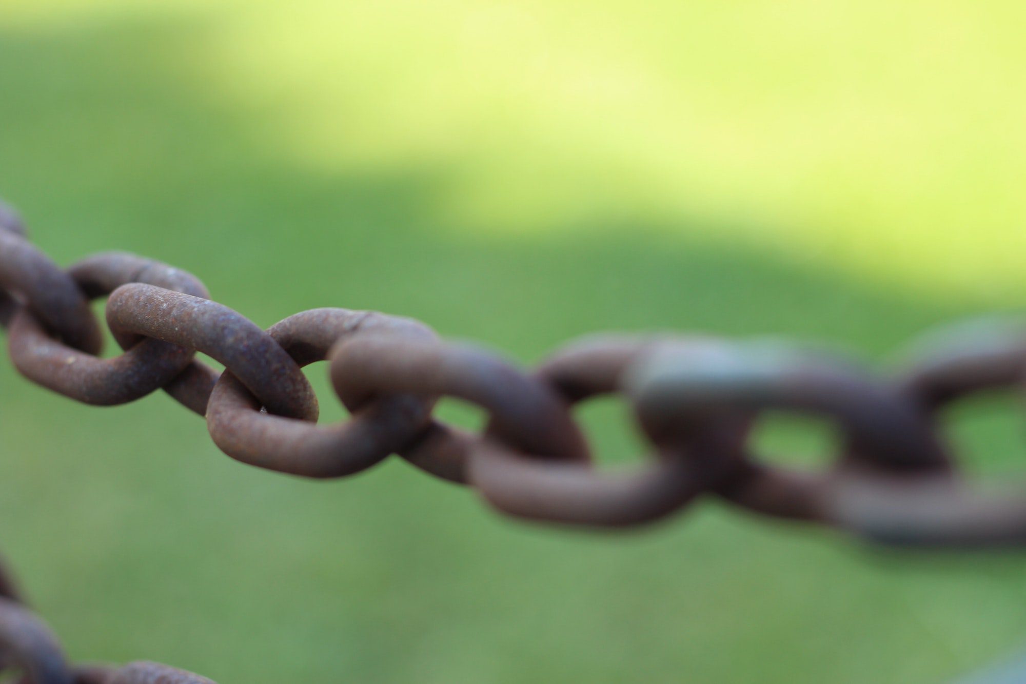 Closeup of a rusted chain Against a green background.