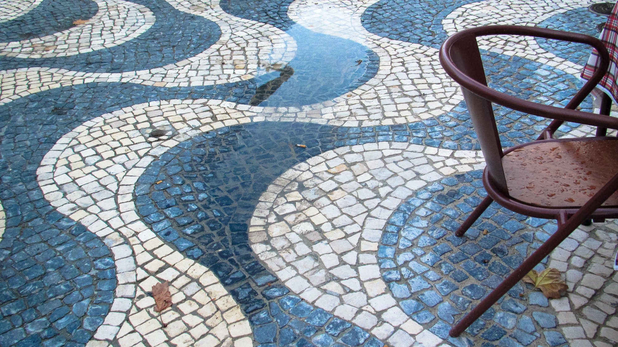 Wet outdoor furniture on a cobbled street. Photo was taken in cascais, portugal in november of 2014